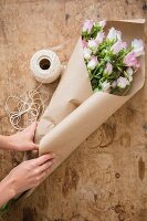 Hands of woman wrapping bouquet in brown paper