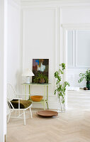 Weißer Stuhl, Tisch mit Bild, Pflanzen, Fischgrätparkett in heller Wohnung