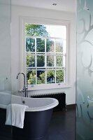 Lattice window and free-standing bathtub on black floor tiles