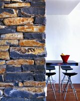 View past stone wall to bar stools around table