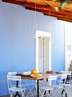 Dining table and chairs against blue wall on Mediterranean terrace
