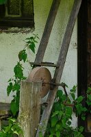 Alter Schleifstein an Hauswand im Garten