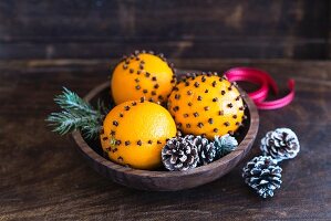 Orange and clove pomanders in wooden bowl (festive)