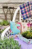 White wicker chair with cushions and fabric-covered tray filled with potted fresh herbs in garden