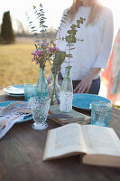 Woman standing next to romantically set table with open book