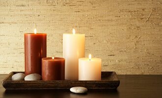 Brown and beige lit candles on rectangular wooden tray