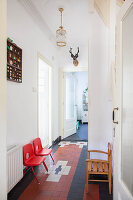 Two red plastic chairs and wooden chair in corridor of period apartment