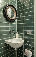 Grüne Wandfliesen in Gäste-Toilette mit Marmor-Handwaschbecken und Wandspiegel