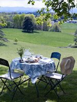 Gedeckter Gartentisch auf dem Rasen mit Blick auf die Landschaft