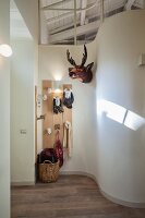 Curved wall in hallway and coat rack with stylised animal heads