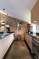 Kitchen worksurface opposite long counter in converted barn with brick wall
