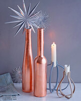 Christmas arrangement of silver stars, copper-coloured bottles and candles