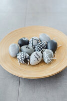 Easter eggs hand-painted in shades of grey on wooden plate