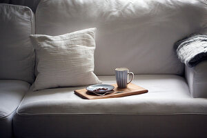 A plate and a cup on a tray on a sofa