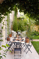 Gedeckter Tisch und schwarze Gartenstühle auf der Terrasse