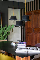 Pendant lamps with hats used as lampshades above table with black top