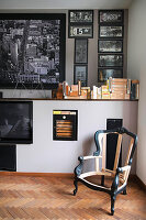 Antique chair frame in corner below collection of black and white photos on wall