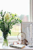 Book, glasses, vase of white flowers, dream catcher and candles on windowsill