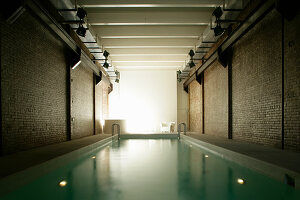 Swimming pool in room with brick walls