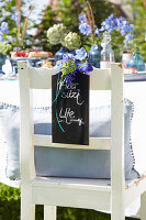 Chair in the garden decorated with place card and blue flowers