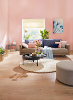 A leather sofa and a round, pivoting coffee table in a living room with pink walls