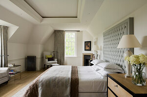 Bed with button tufted headboard in bedroom with coffered ceiling