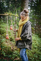 Mädchen hängt selbstgemachte Vogelfutterstation im Wald auf