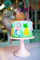 Cake ornately decorated with flamingo and pineapple motifs
