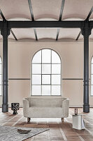 Modern, oval sofa in old factory building with metal pillars