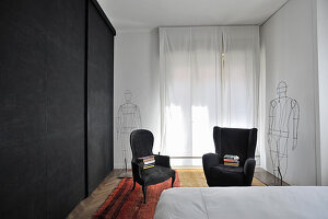 Schwarzer Kleiderschrank, schwarze Sessel und Draht-Skulpturen im Schlafzimmer