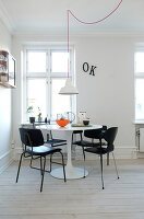 Black chairs around a white designer table in a minimalist dining room