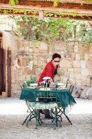 Woman with sunglasses setting a table on a Mediterranean terrace