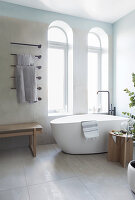 A free-standing bathtub in front of arched windows