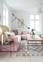 Pink upholstered suite, golden table lamp and rustic coffee table in the living room