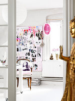 A golden Buddha in front of an open door to an office with a collage on the wall