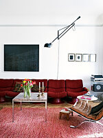 Red retro sofa in the living room with red carpet and wall lamp