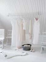 Clothes rail under the eaves of a sloping ceiling in a white bedroom