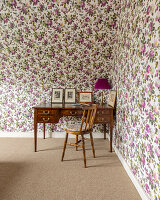 Old chair and antique desk against floral wallpaper