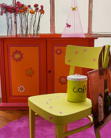 Furniture in bold colours: neon green chair in front of red and orange cabinet