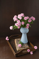 Vase of pink asters on antique wooden tray