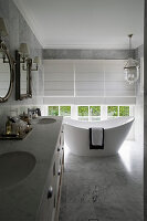 Twin sinks and modern, free-standing bathtub next to window in marble bathroom
