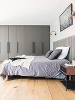 Doppelbett und grauer Einbauschrank im Schlafzimmer
