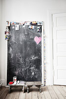 Photos stuck on chalkboard next to two wooden stools