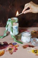 Lighting handmade scented candles with flowers in jars
