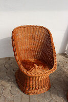 Wicker easy chair against white wall in courtyard