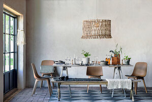 Rustikaler Holztisch mit Geschirr und Zimmerpflanzen, Stühle und Sitzbank