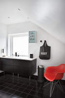 Red designer chair in black-and-white bathroom with sloping ceiling