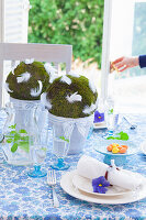 Handmade moss balls with feathers decorating Easter table