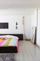 Doppelbett mit gestreifter Decke in weißem Schlafzimmer mit Holzdielenboden