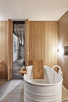 Free-standing bathtub in bathroom with wood-clad walls